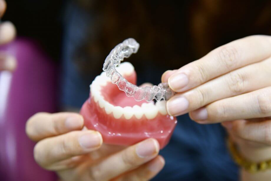 clear dental aligners being placed on model of teeth
