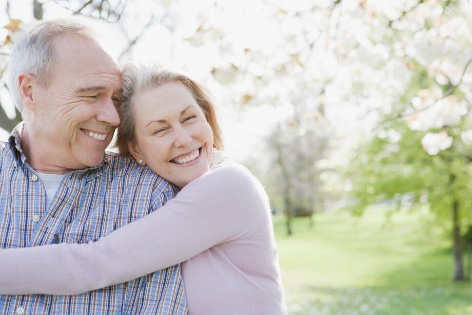 older couple smiling and hugging in the park