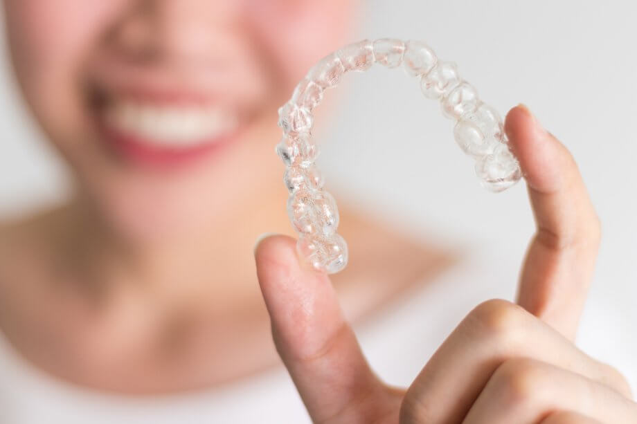 Smiling Woman Holding Invisalign braces