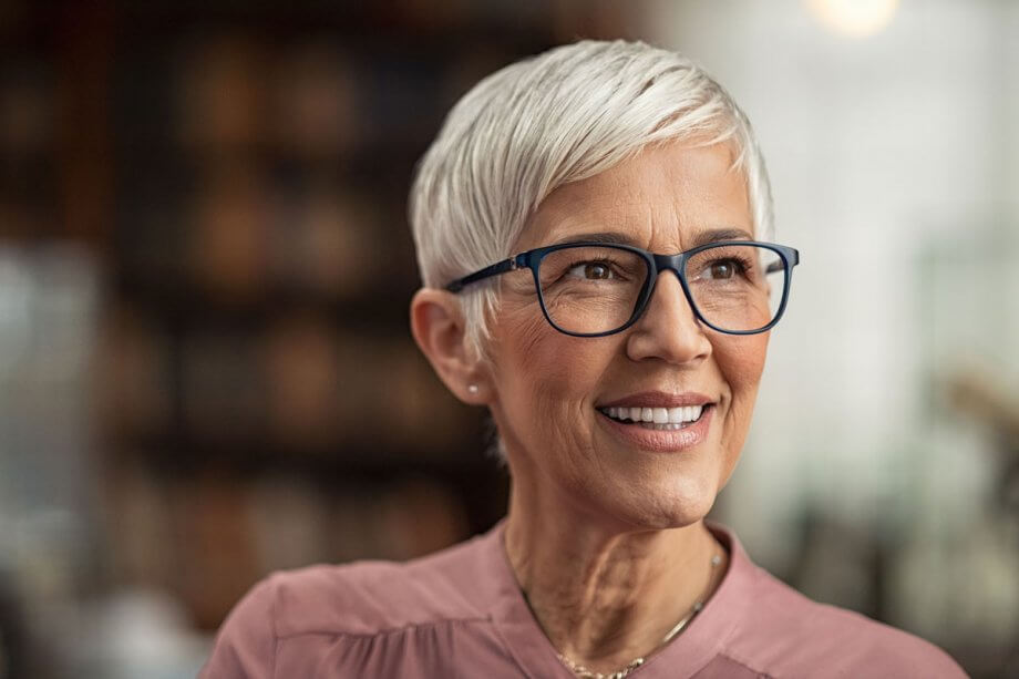 older woman in glasses and short hair smiling, looking off to the right