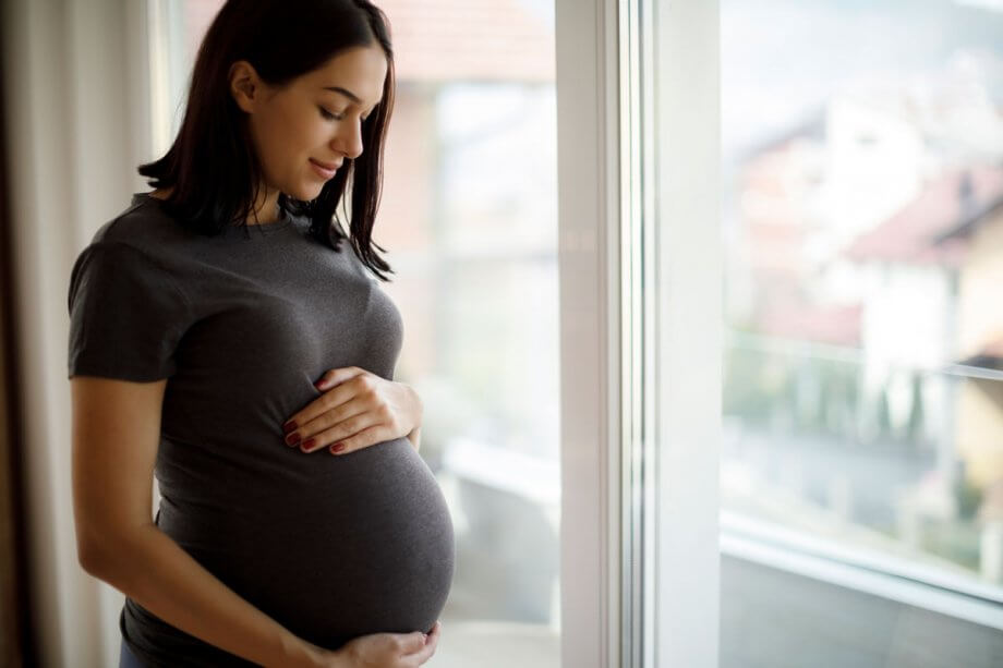 pregnant woman standing by woman holding her belly